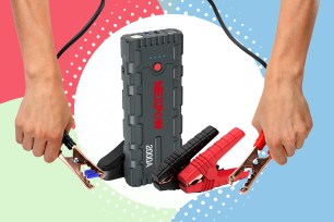 A hand holding a battery connected with jumper cables