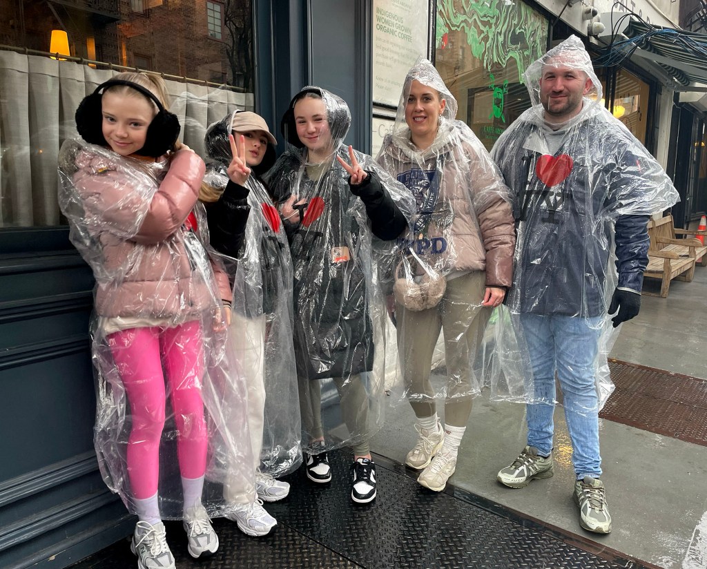 Grace Van Patten and other people wearing rain ponchos at Tea and Sympathy in rainy Manhattan, expressing get-well wishes for Princess Kate