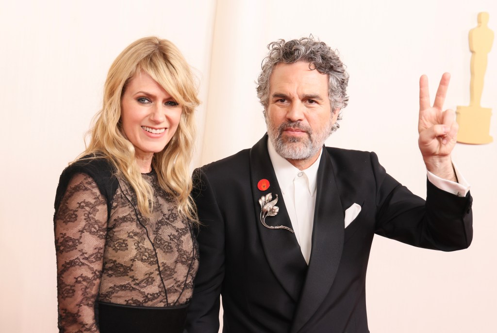 Mark Ruffalo holds up a peace sign as he attends the Oscars with his wife, Sunrise Coigney.