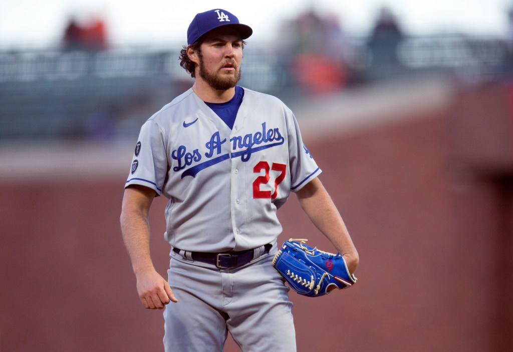 Trevor Bauer in Dodgers uniform standing on a baseball field, looking towards home plate with a focused expression.