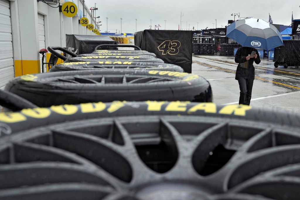 A member of the media walks past a stack of racing tires after the NASCAR Daytona 500 auto race