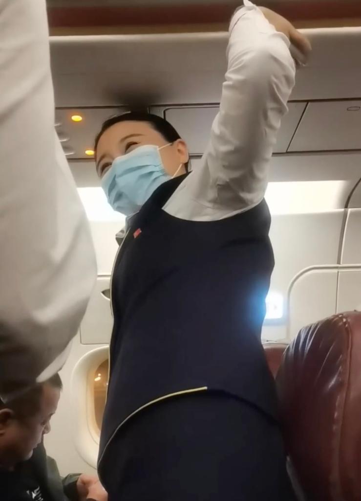 A flight attendant on a Chinese airline was forced to hold an emergency exit door shut after an allegedly drunk passenger tried to opened it.