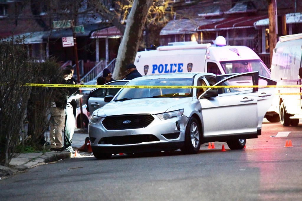 NYPD officers investigate scene of officer-involved shooting in Brooklyn, where a car with its four doors open is behind crime scene tape. 