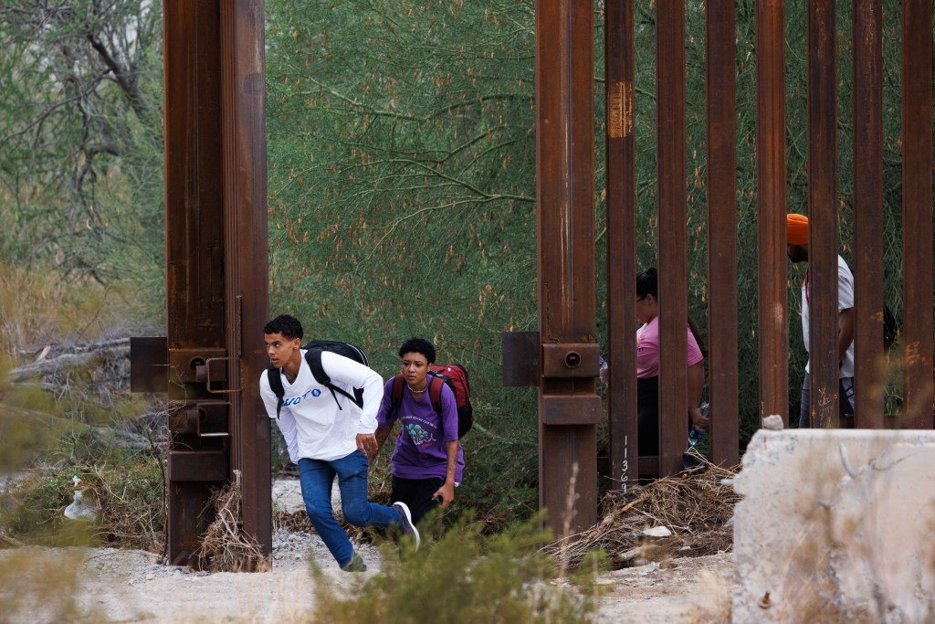 Migrants pass through an open monsoon gate in the border wall near Lukeville, Arizona.