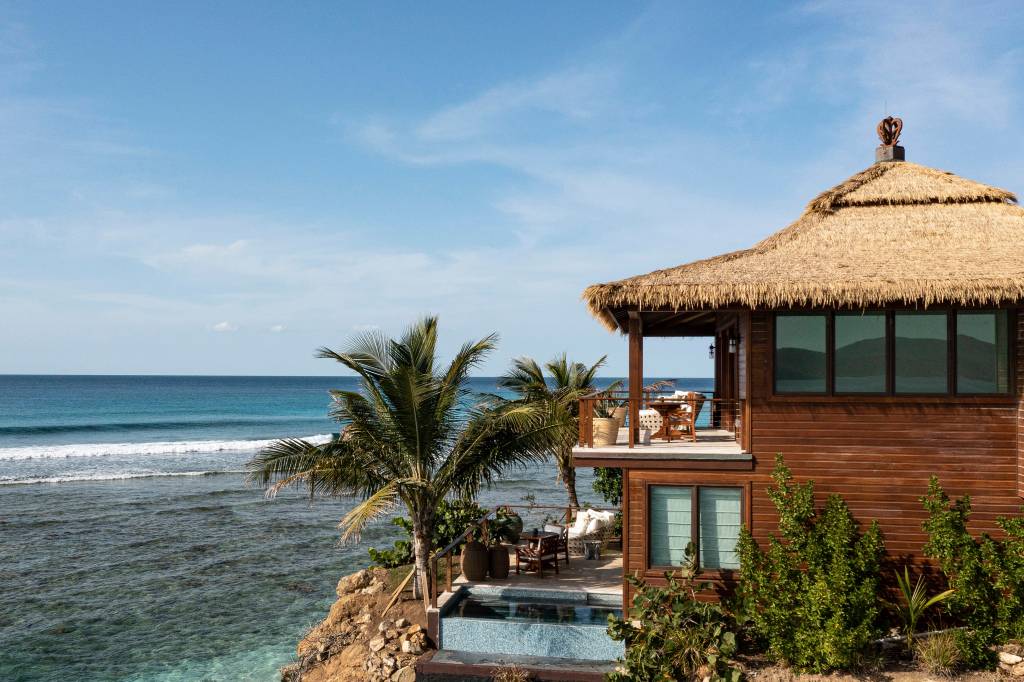 a house with a thatched roof and a pool overlooking the ocean