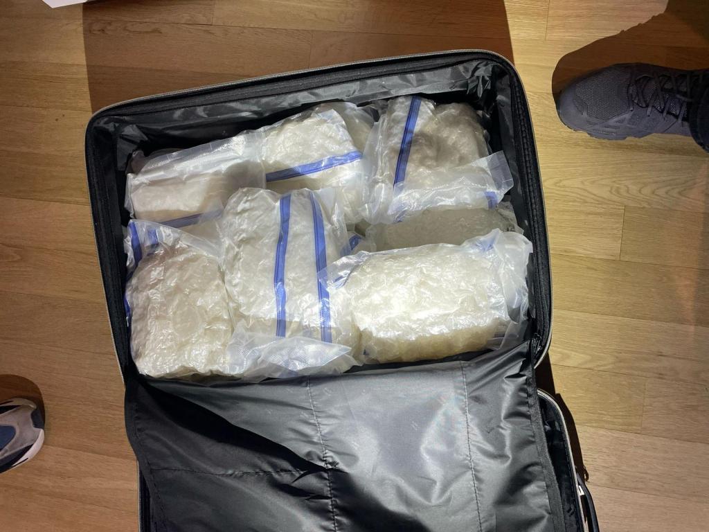 A suitcase containing several clear plastic bags of drugs.