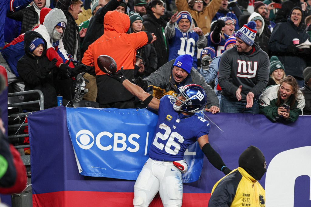 Giants running back Saquon Barkley (26) gives the game ball to a young fan after scoring his second touchdown of the game