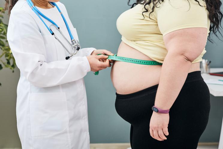 Nutritionist inspecting a woman's waist using a meter tape to prescribe a weight loss diet