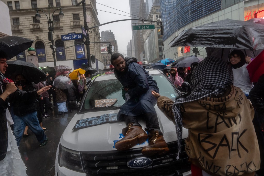 A person climbs on an NYPD vehicle during a protest in support of Palestine in Manhattan, New York