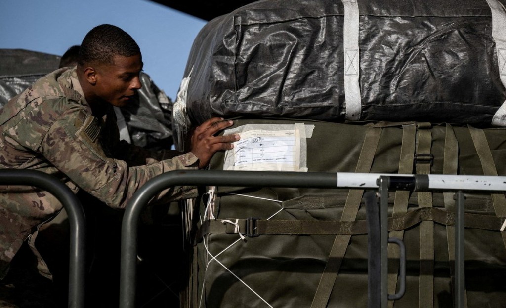 A camoflague-wearing American soldier from the United States Central Command checks a label on a bundle of humanitarian aid for Gaza