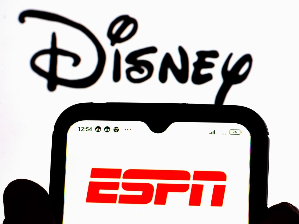 ESPN logo displayed on a smartphone screen with the Disney logo in the background.