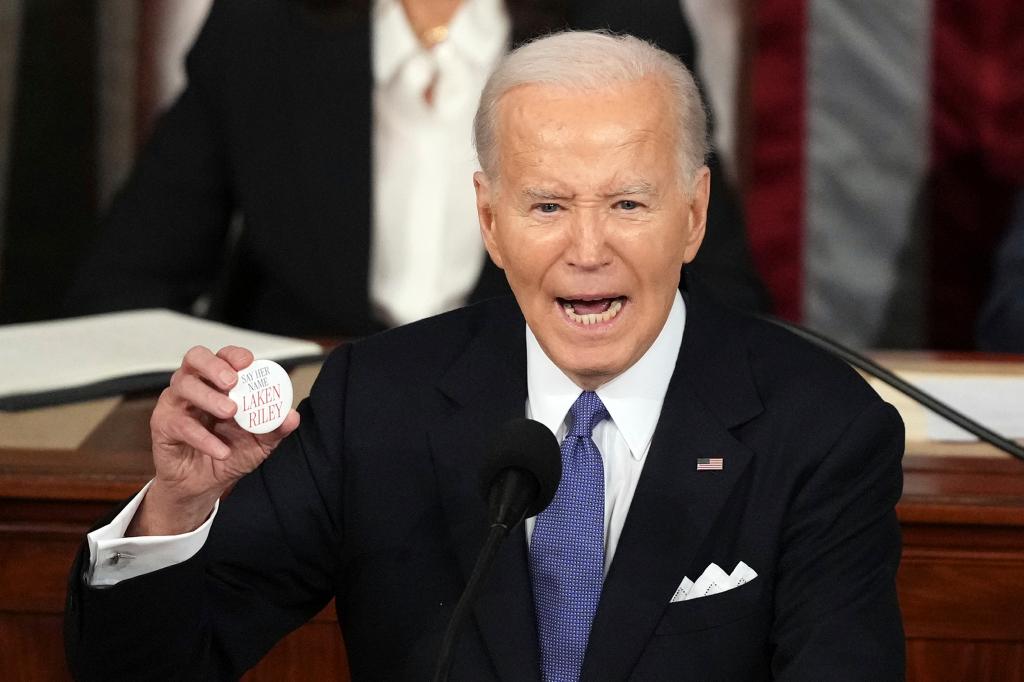 President Joe Biden holds up a Laken Riley button as he delivers the State of the Union address.