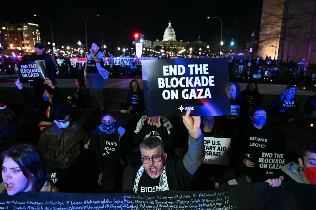 Protesters are seen holding "end the blockage on Gaza" signs.