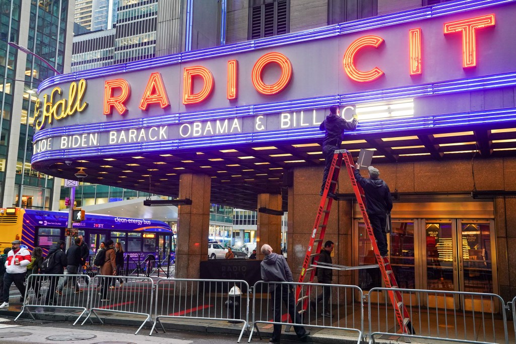 Preparation activities at Radio City Music Hall, NYC for Joe Biden's fundraiser, including signage installation, street cleaning, and K-9 security checks