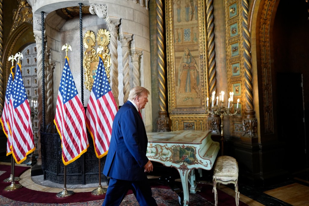 Donald Trump walking in a room with flags.