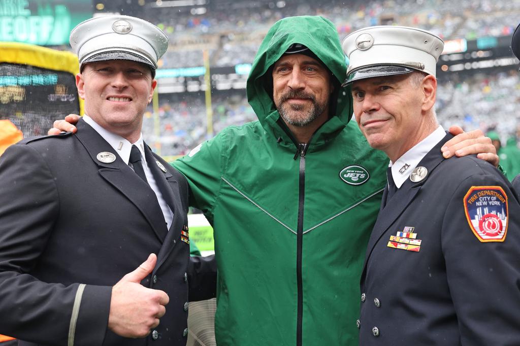 New York Jets quarterback Aaron Rodgers #8, poses for a photo with members of the FDNY before the game.