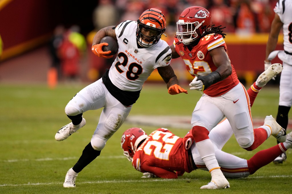 Joe Mixon of the Cincinnati Bengals runs with the ball and Nick Bolton of the Kansas City Chiefs defends in an NFL football game.