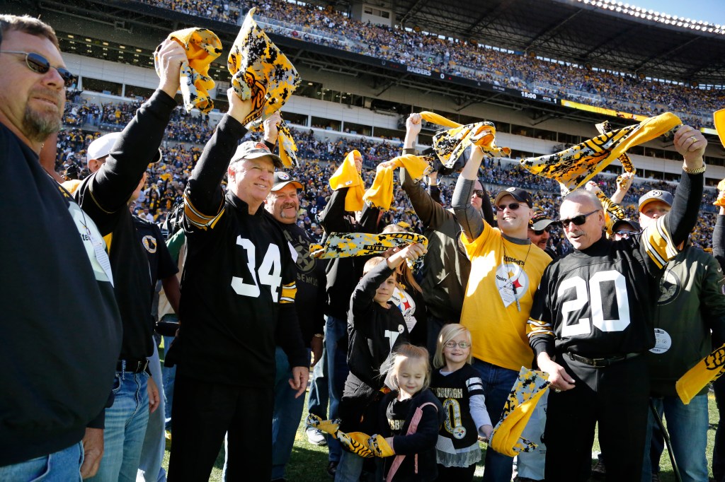 Former Pittsburgh Steelers Andy Russell and Rocky Bleir lead the Terrible Towel twirl before a football game in a stadium. Rocky Bleier detected.