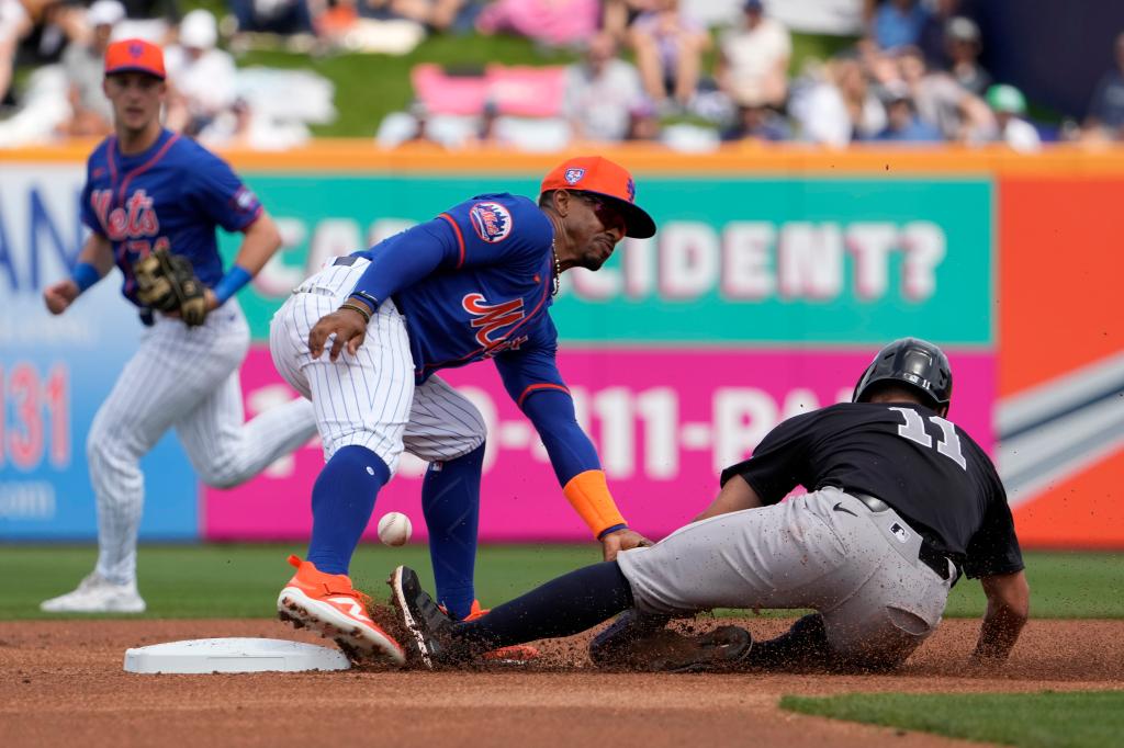 Francisco Lindor tries to tag Anthony Volpe on a stolen base attempt during a Mets-Yankees spring training game.