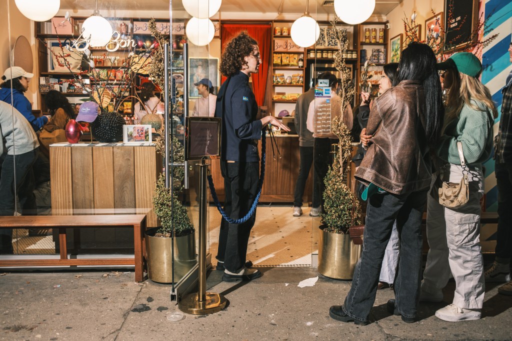 A bouncer named Sage talks to people lining up outside the BonBon candy store. 