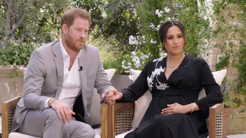 Prince Harry and Meghan Markle sitting on a chair talking to Oprah Winfrey.