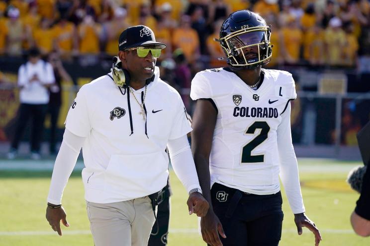 Colorado head coach Deion Sanders, left, talks with his son and starting quarterback Shedeur Sanders (2) prior to an NCAA college football game against Arizona State, Saturday, Oct. 7, 2023, in Tempe, Ariz.
