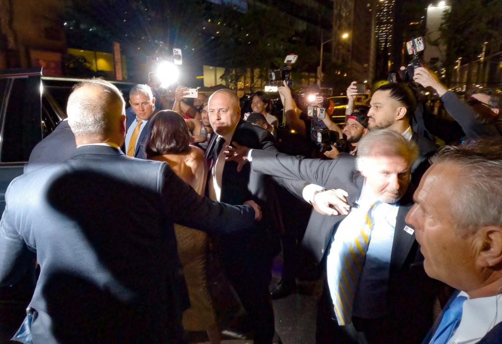 Prince Harry and Meghan Markle are escorted by security through a group of photographers outside The Ziegfeld Theatre in New York City.