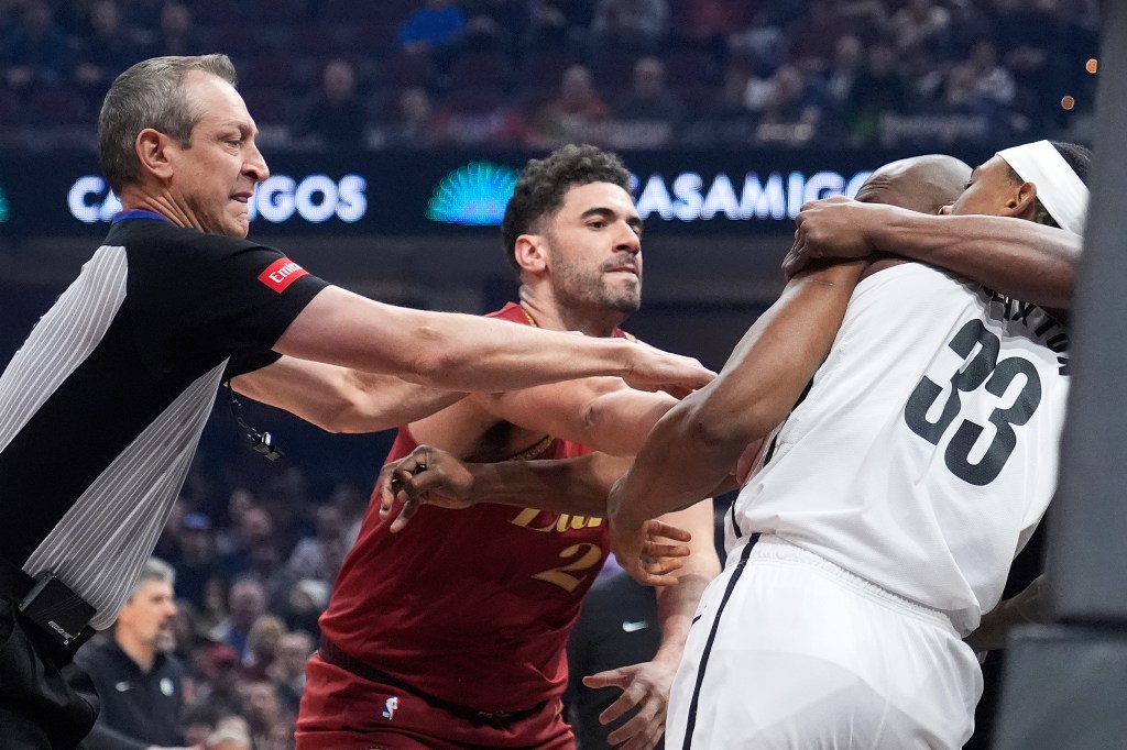 Cavaliers forward Georges Niang, center, and Brooklyn Nets center Nic Claxton (33) are separated by referee J.T. Orr, left, and referee Courtney Kirkland (61), second from right, in the first half of an NBA basketball game.