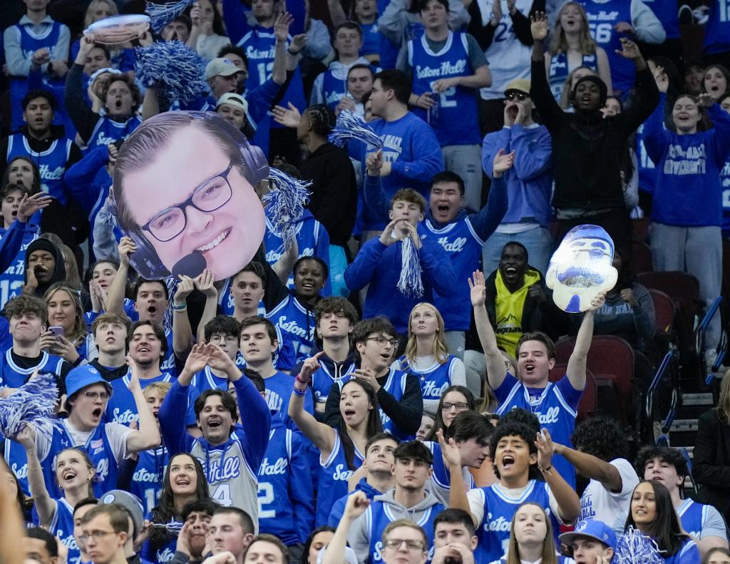 Seton Hall Pirates student section cheering at a game, holding a poster of Fox Sports announcer John Fanta