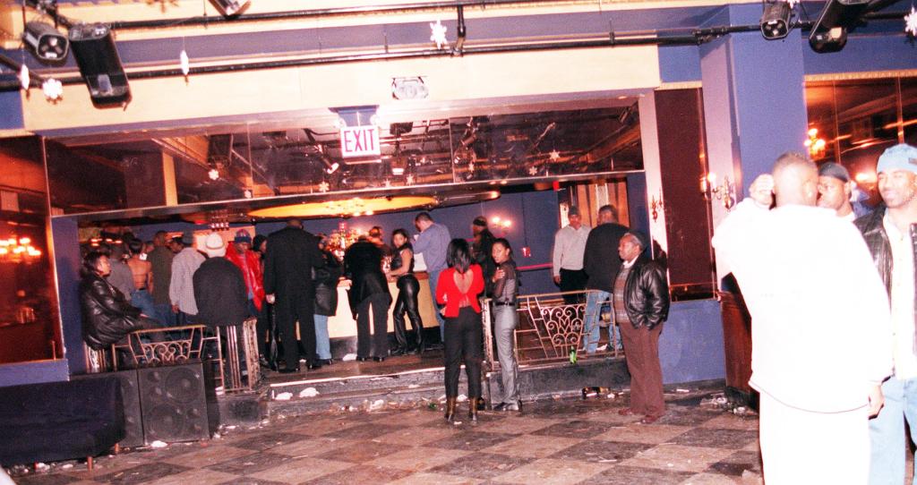 Interior of Club New York after a shooting incident, showing attendees waiting to be questioned by police.