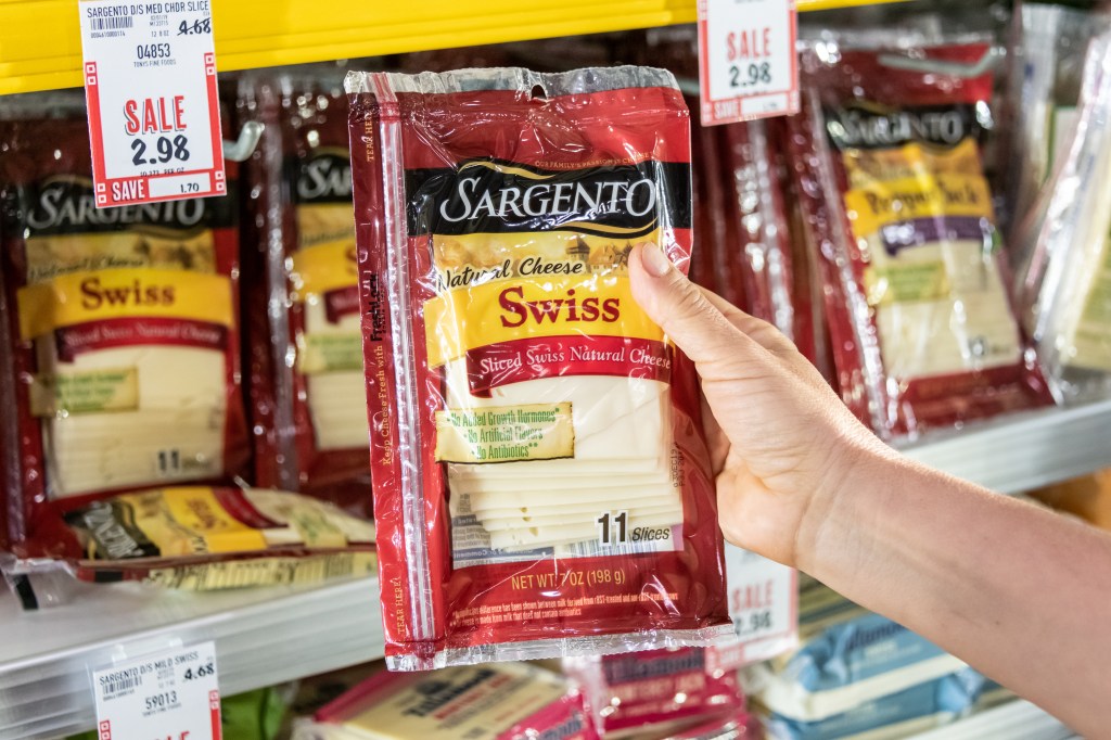 Shoppers hand holding a package of Sargento brand sliced natural swiss cheese 