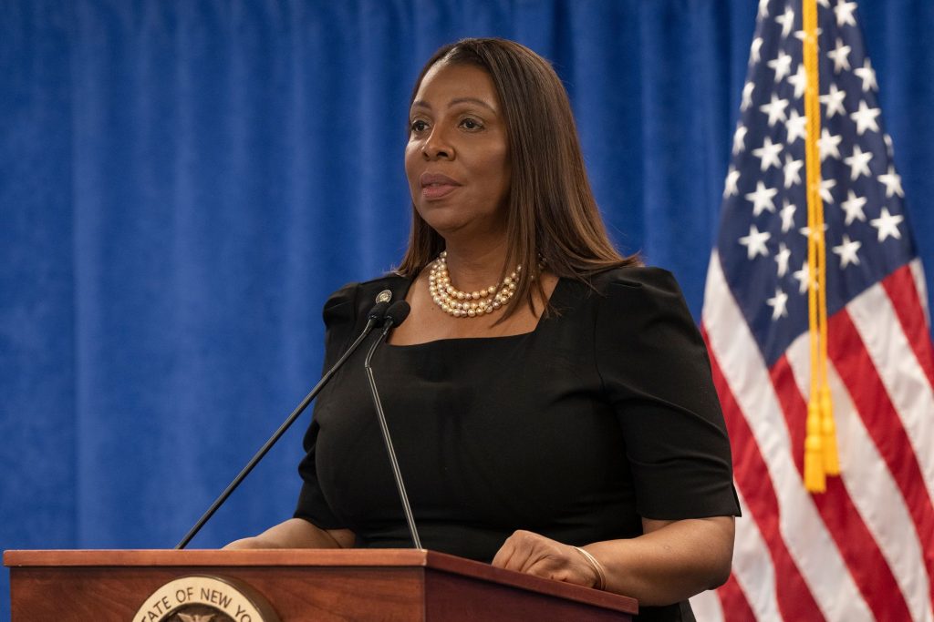 A woman, Letitia James, speaking into a microphone at a podium in front of a crowd of people.