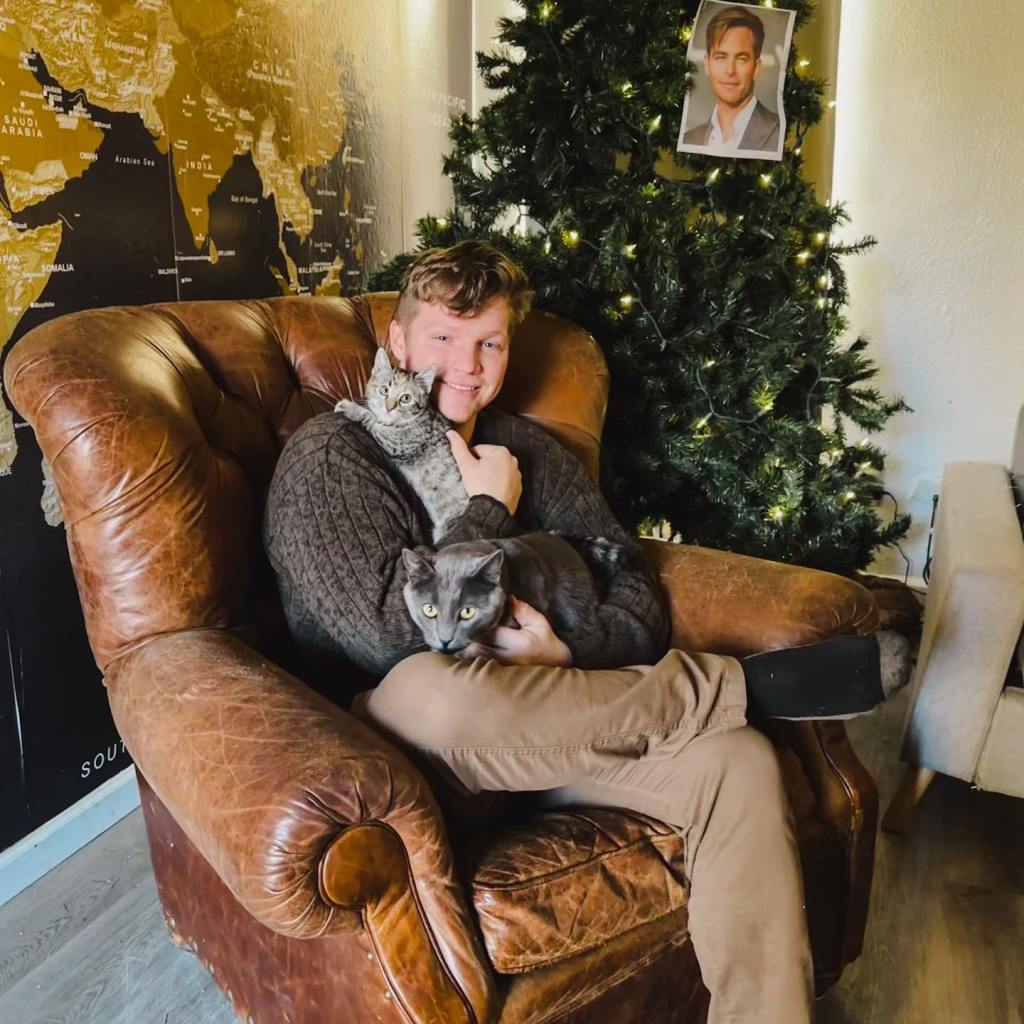 Garrison Brown smiling holding cats. 