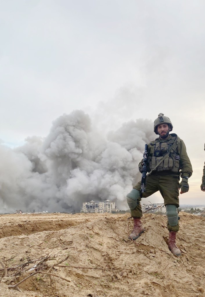 Kakiashvili, seen here in uniform, helmet and with long gun, as a billowing cloud of grey smoke rises behind him in the distance