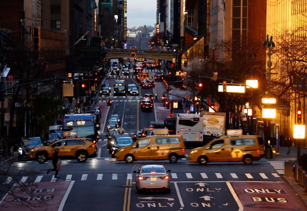 Taxi cabs crossing a city street at sunrise in New York City.