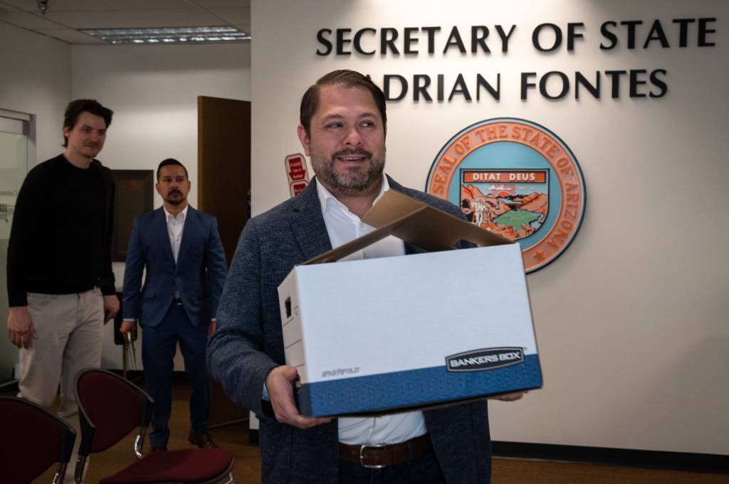 A man, Ruben Gallego, holding a box while submitting signatures to the Secretary of State's office for his U.S. Senate candidacy in Phoenix.
