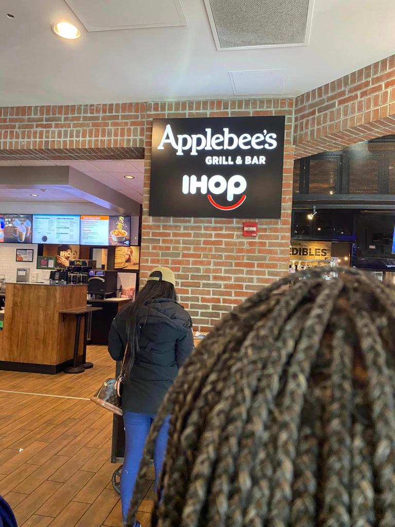 Applebee's/IHOP combo restaurant exterior in Detroit with a sign and outdoor seating area in front of a brick building.