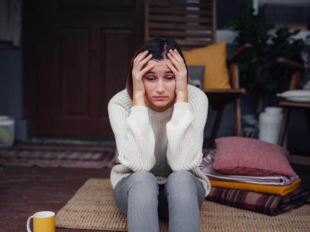 Young depressed asian woman sitting on porch of backyard.