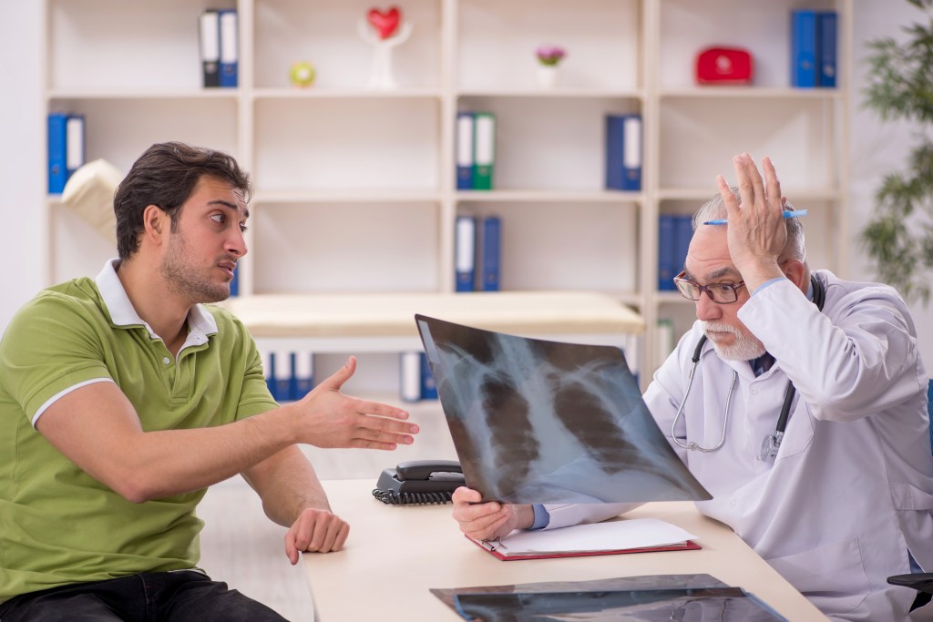 Young male patient discussing an X-ray with his older male radiologist doctor