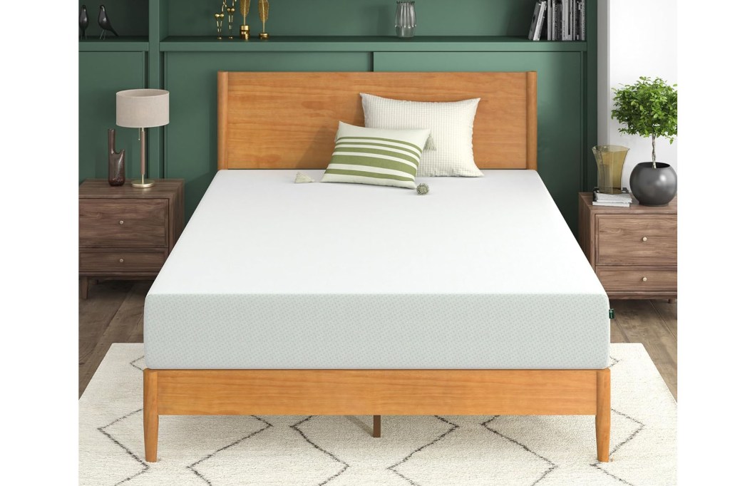 A bed with a white Zinus mattress against a green wall