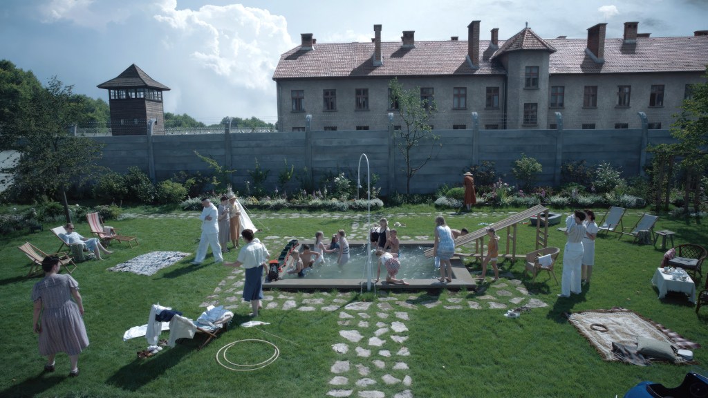 A movie still from "The Zone of Interest" showing several children playing in front of a building.