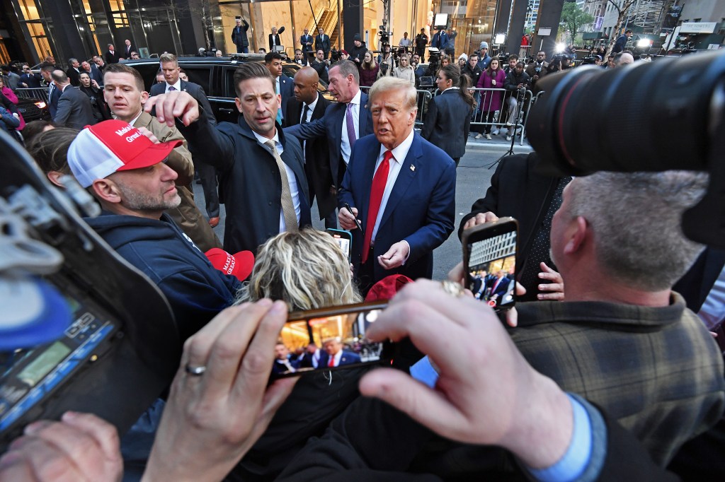 Former President Donald Trump in a suit and tie, conversing with construction workers at the JPMorgan Chase headquarters construction site in midtown Manhattan, New York.