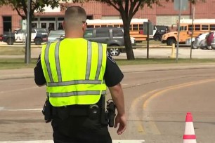 Police officer in a yellow vest at press conference regarding Bowie High School shooting in Texas