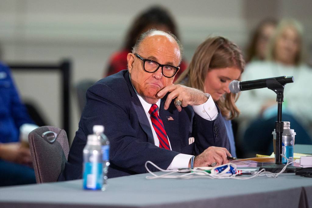 President Donald Trump's attorney Rudy Giuliani (right) listens to presenters at a public meeting where supporters of President Trump disputed his defeat in the 2020 election.