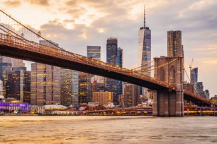 New York City skyline at sunset with Brooklyn Bridge and Lower Manhattan.