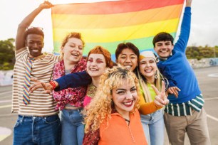 Young people holding a LGBT rainbow flag.