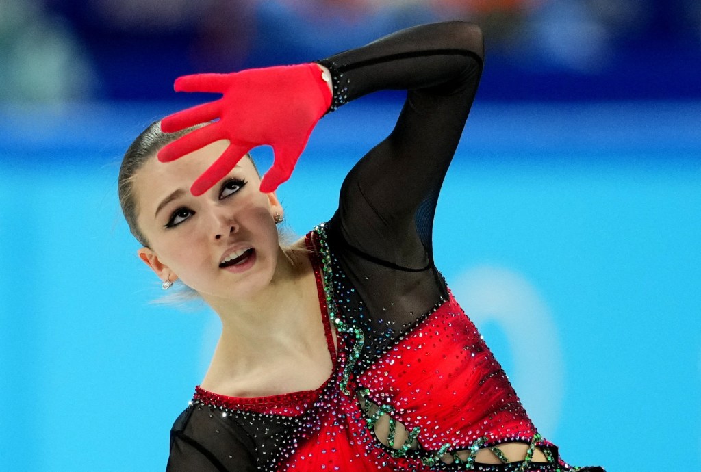 Kamila Valieva of the Russian Olympic Committee performing during Women's Single Free Skating event at 2022 Beijing Olympics in Capital Indoor Stadium, dressed in red and black.