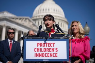 Chloe Cole speaking at a podium on Capitol Hill, with Rep. Marjorie Taylor Greene looking on during a news conference about the Protect Children's Innocence Act
