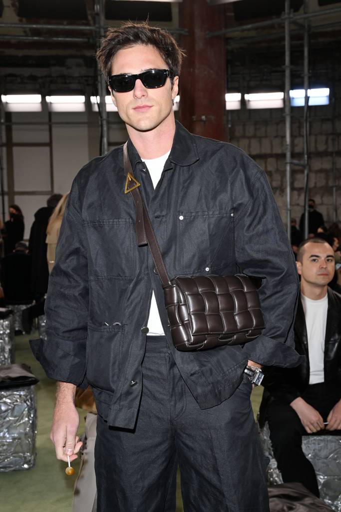 Jacob Elordi at Bottega Veneta Winter 2022 fashion show, wearing sunglasses and a black jacket, carrying designer handbag