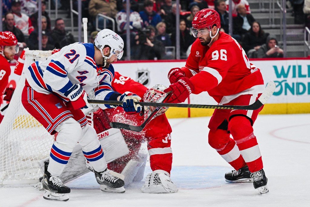 Detroit Red Wings goaltender Alex Lyon (34) makes a save in front of defenseman Jake Walman (96) and New York Rangers center Barclay Goodrow (21) during the game at Little Caesars Arena. 